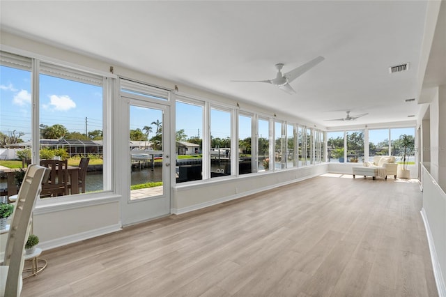 unfurnished sunroom with a water view, ceiling fan, and wood finished floors
