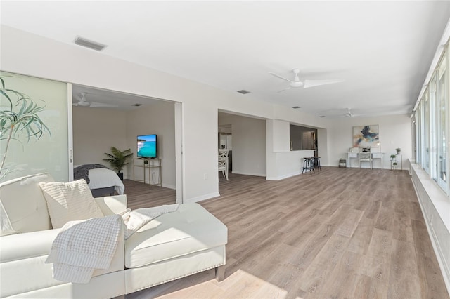 living room featuring light wood-type flooring, ceiling fan, and visible vents