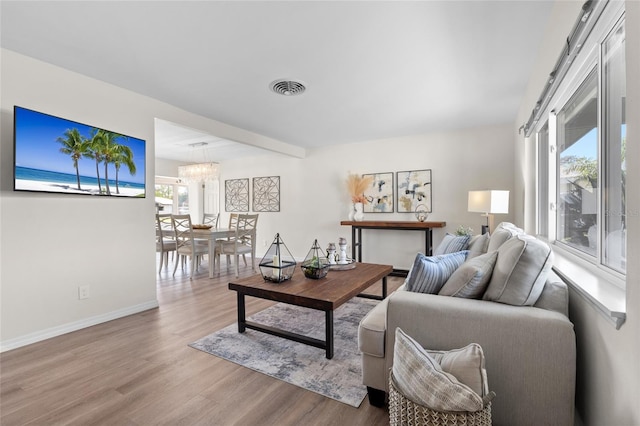 living room featuring a chandelier, wood finished floors, baseboards, and visible vents