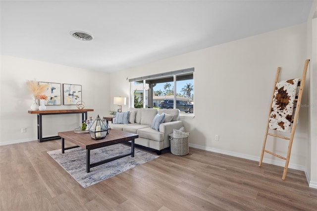 living room with visible vents, light wood-style flooring, and baseboards