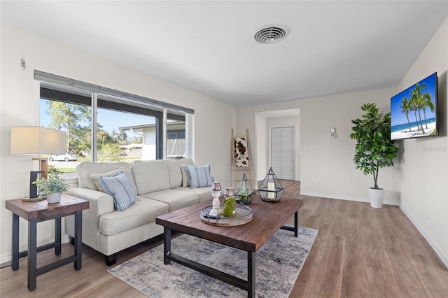 living area featuring wood finished floors, baseboards, and visible vents