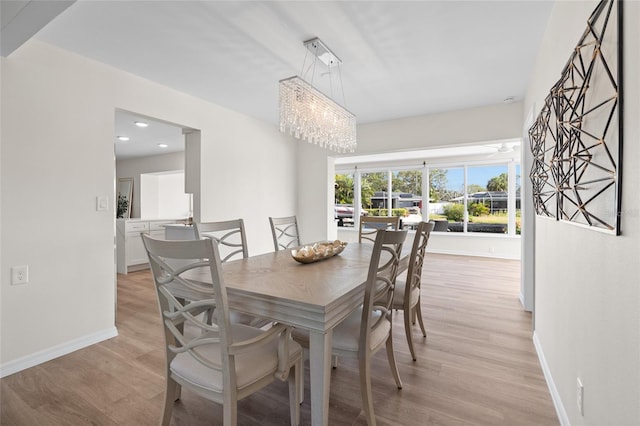 dining space with light wood-style flooring, recessed lighting, a notable chandelier, and baseboards