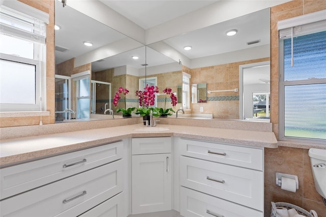 full bath with a wealth of natural light, visible vents, tile walls, and a stall shower