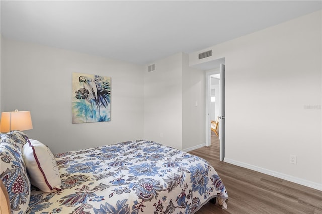 bedroom featuring wood finished floors, baseboards, and visible vents