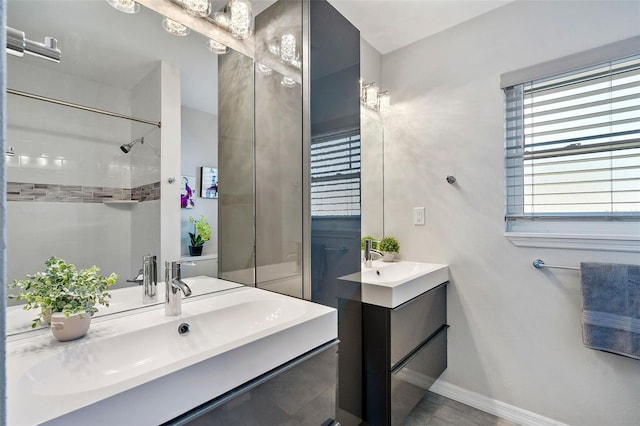 full bath featuring a sink, two vanities, and baseboards