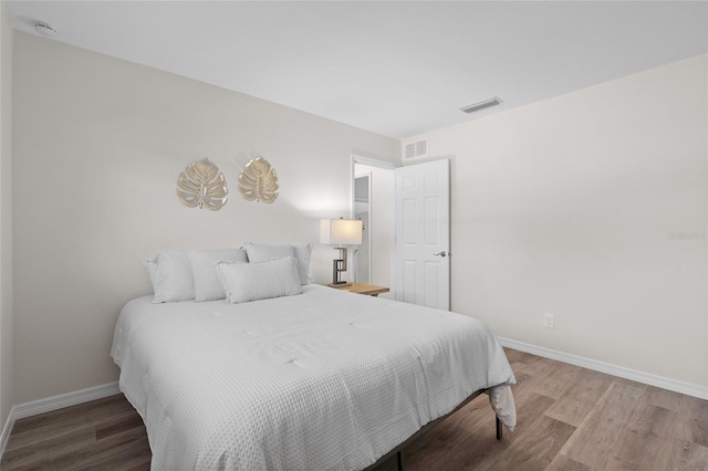 bedroom with visible vents, baseboards, and wood finished floors