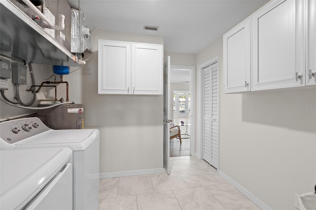 laundry area with washer and dryer, water heater, baseboards, and cabinet space