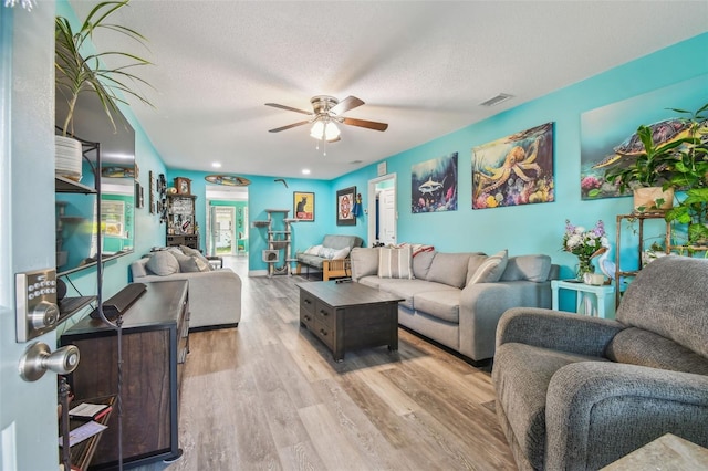 living room with a textured ceiling, light hardwood / wood-style flooring, and ceiling fan