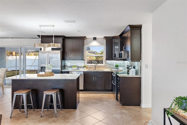 2461 61st Ln N, Saint Petersburg, FL 33710 - kitchen featuring appliances with stainless steel finishes, decorative backsplash, a center island, and dark brown cabinetry