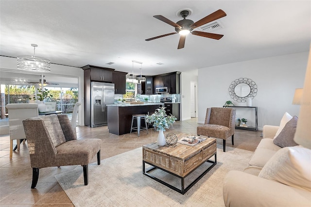 living room with ceiling fan with notable chandelier and sink