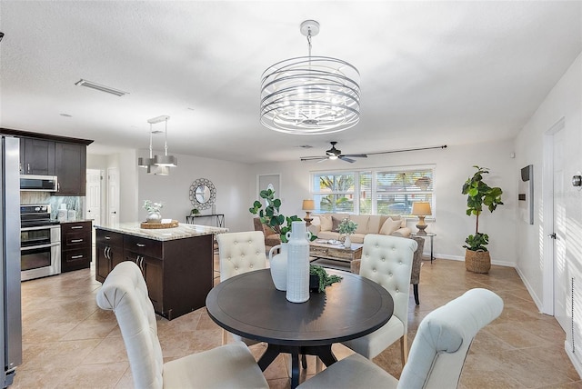 tiled dining area featuring ceiling fan with notable chandelier