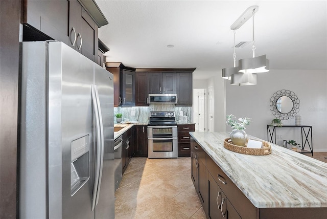 kitchen featuring dark brown cabinetry, light tile patterned floors, tasteful backsplash, a kitchen island, and appliances with stainless steel finishes