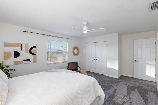 bedroom with ceiling fan, dark carpet, and a closet