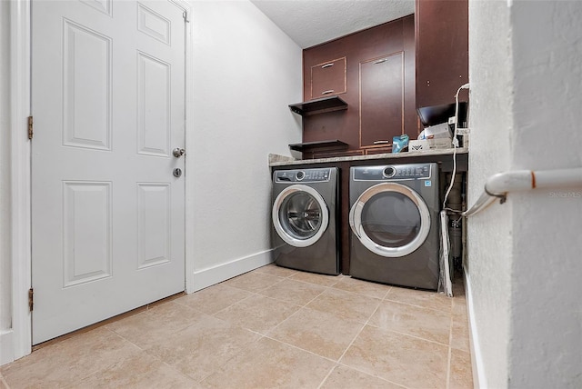 washroom featuring washer and clothes dryer, light tile patterned flooring, and a textured ceiling