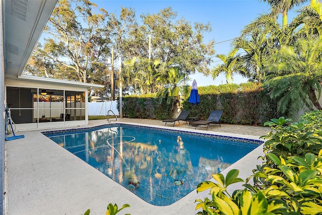 view of swimming pool featuring a sunroom and a patio