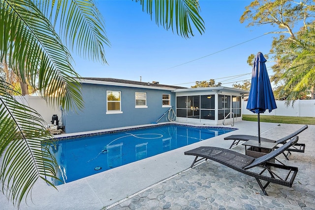 view of pool with a sunroom and a patio area