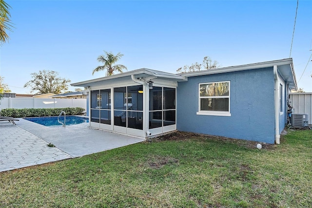 back of house with a lawn, a sunroom, central AC, a fenced in pool, and a patio area