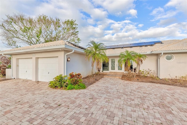 view of front of home with solar panels, a garage, and french doors