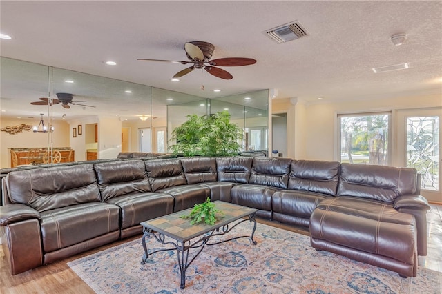 living room with ceiling fan, a textured ceiling, and light hardwood / wood-style flooring