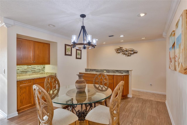 dining room with light wood-type flooring, ornamental molding, and a chandelier