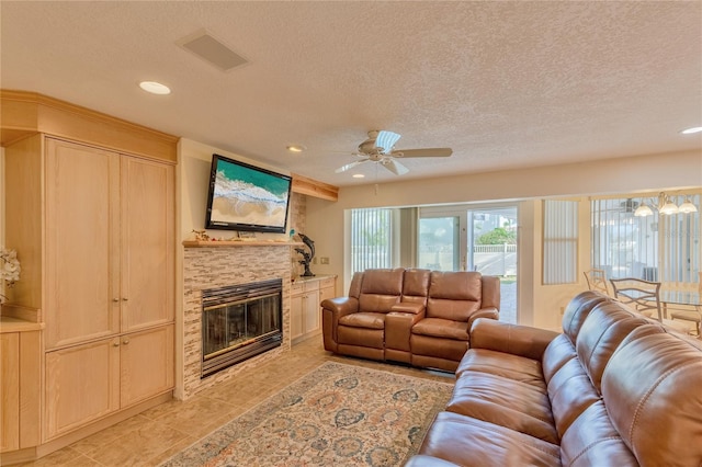 living room with ceiling fan, a fireplace, and a textured ceiling