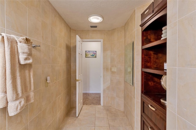 bathroom featuring a textured ceiling, tile patterned floors, and tile walls