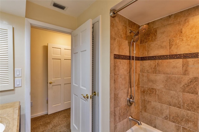 bathroom featuring tiled shower / bath combo and vanity