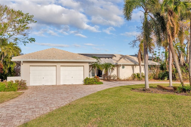 ranch-style home with a front yard, solar panels, and a garage