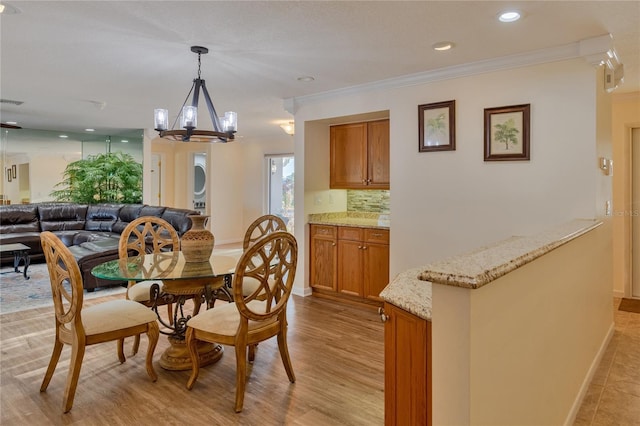 dining space featuring crown molding, a chandelier, and light hardwood / wood-style floors