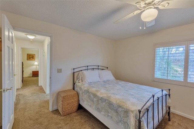 bedroom with ceiling fan, light colored carpet, and a textured ceiling