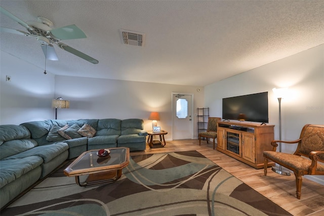 living room featuring ceiling fan, a textured ceiling, and light wood-type flooring