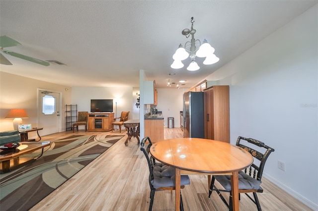 dining area featuring ceiling fan with notable chandelier and light wood-type flooring