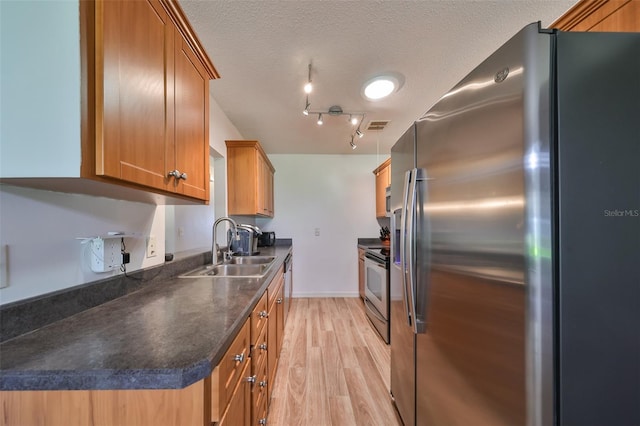 kitchen featuring a textured ceiling, stainless steel appliances, light hardwood / wood-style flooring, and sink