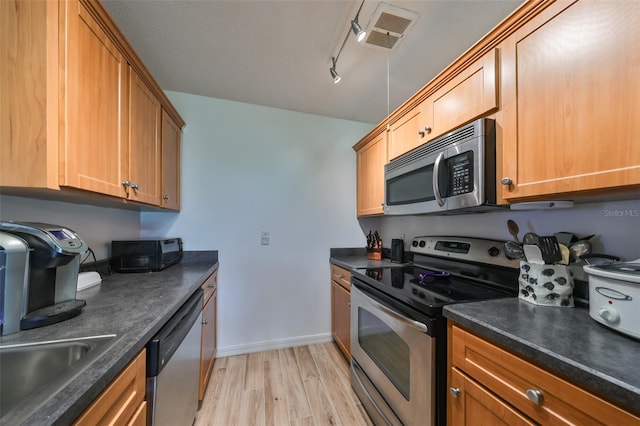 kitchen featuring light wood-type flooring, stainless steel appliances, rail lighting, and sink