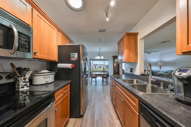 kitchen featuring ceiling fan with notable chandelier, sink, light hardwood / wood-style flooring, a textured ceiling, and stainless steel appliances