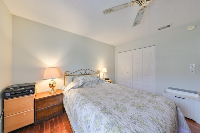 bedroom featuring a textured ceiling, dark hardwood / wood-style floors, a closet, and ceiling fan