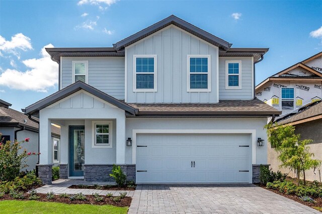 7757 Somersworth Dr, Kissimmee, FL 34747 - view of front of property featuring board and batten siding, stone siding, a garage, and decorative driveway