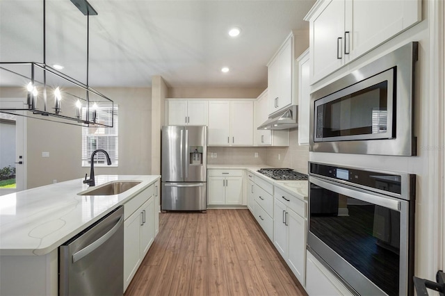 kitchen with white cabinetry, sink, light stone counters, appliances with stainless steel finishes, and light wood-type flooring