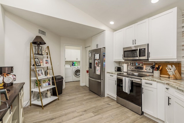 kitchen with washing machine and clothes dryer, white cabinets, stainless steel appliances, and light hardwood / wood-style floors