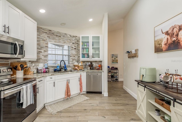 kitchen with light stone counters, white cabinetry, sink, and appliances with stainless steel finishes