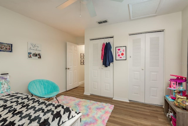 bedroom featuring hardwood / wood-style flooring, ceiling fan, and multiple closets