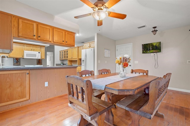 dining room with light hardwood / wood-style flooring, ceiling fan, and sink