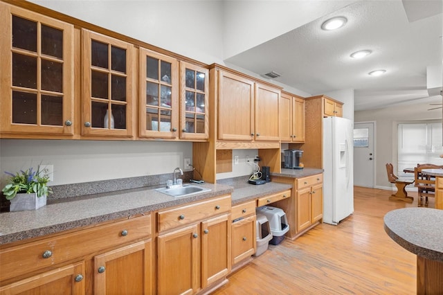 kitchen with light hardwood / wood-style floors, vaulted ceiling, white fridge with ice dispenser, and sink