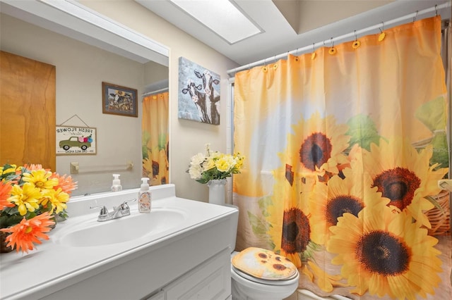 bathroom with vanity, toilet, and a skylight