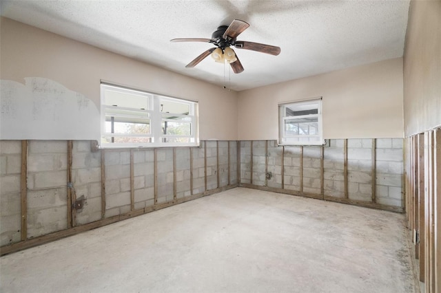 empty room with tile walls, ceiling fan, concrete floors, and a textured ceiling