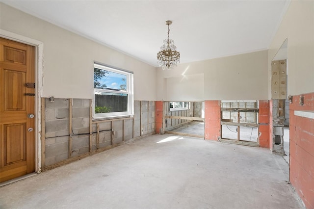 empty room with concrete flooring and a notable chandelier