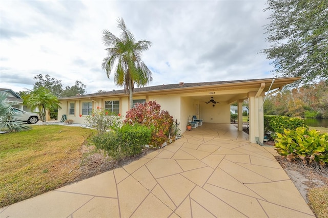 exterior space featuring ceiling fan, a front lawn, and a carport