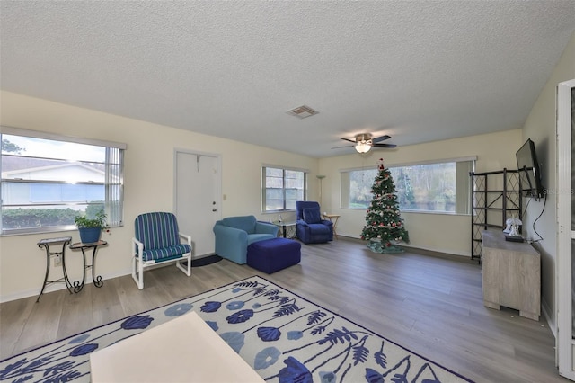 sitting room with ceiling fan, wood-type flooring, and a textured ceiling