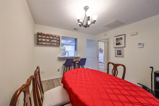 dining room featuring hardwood / wood-style flooring, a textured ceiling, and a chandelier