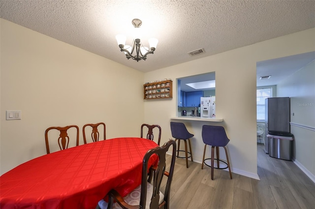 dining space with hardwood / wood-style floors, a chandelier, and a textured ceiling